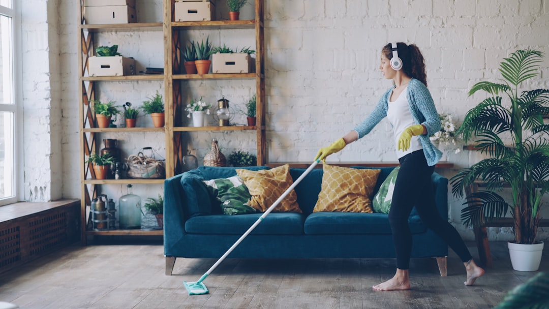 services-img Cheerful young woman is dancing with mop during routine clean-up in nice loft style apartment, she is listening to music with wireless headphones and singing enjoying her occupation.