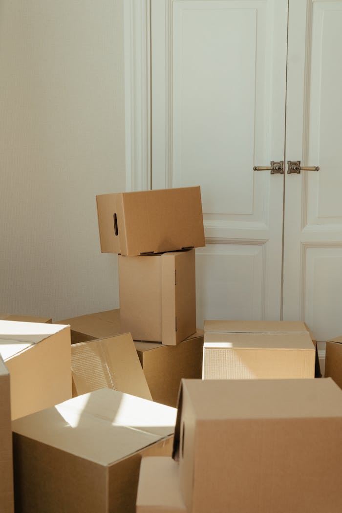 services-01 Stack of cardboard boxes by a white wooden door, perfect representation of moving day readiness.